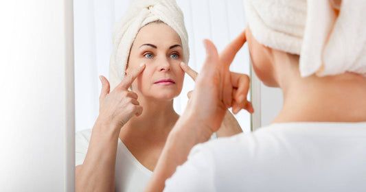 Woman in mirror applying cream to face