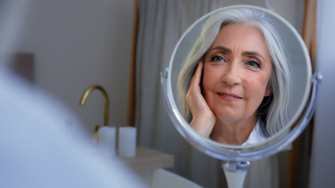 Woman in mirror applying cream to face